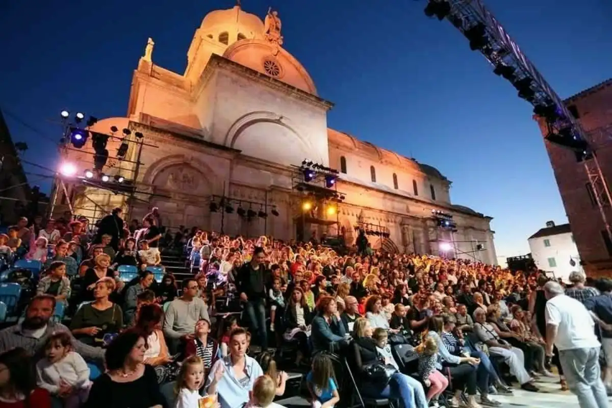 Crowd at an outdoor festival event in front of Šibenik's Cathedral of St. James in the evening