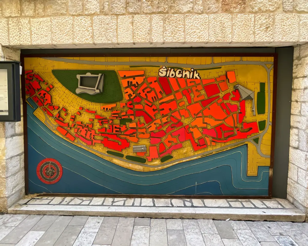 Colorful three-dimensional relief map of Šibenik's old town displayed on a wall, highlighting streets and landmarks for navigation.