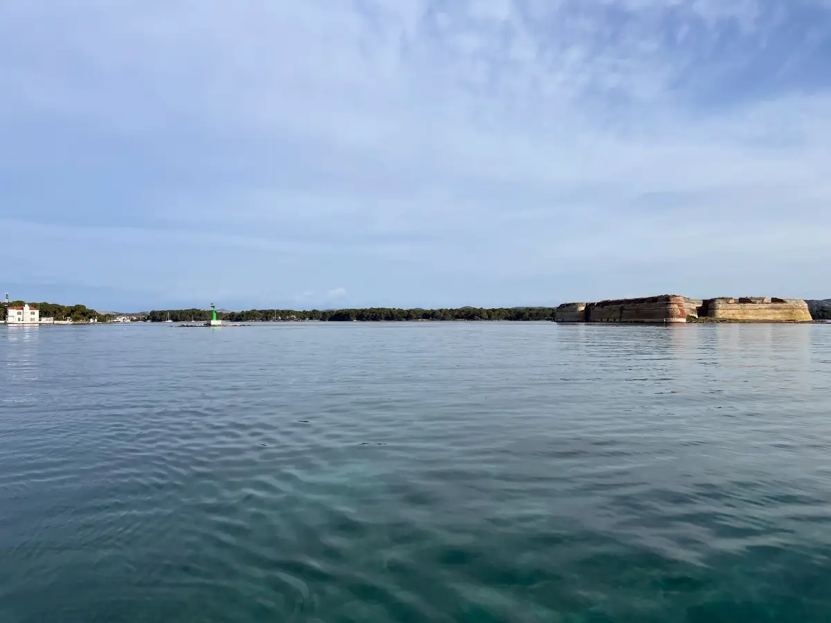 View from the water of St. Nicholas Fortress at a distance, with its massive walls standing strong against the tranquil sea in Šibenik