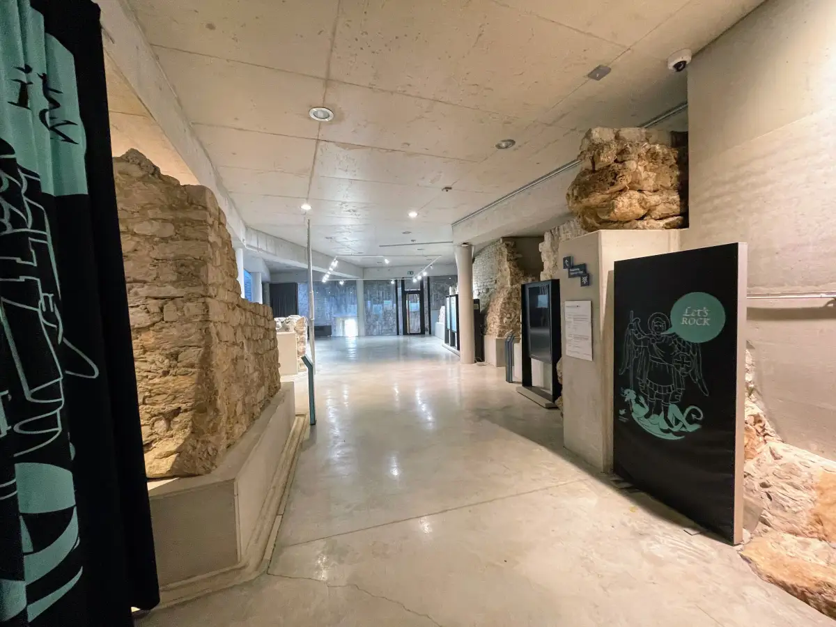 Interior view of the Šibenik fortress museum with exposed stone walls, modern displays, and polished concrete floors, blending historical elements with contemporary design.