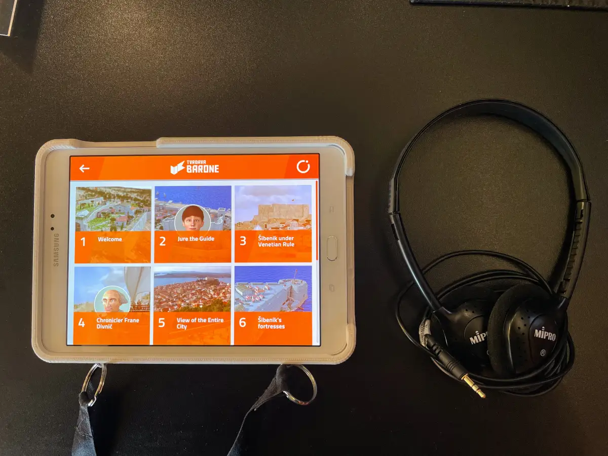 Audio guide tablet with headphones displaying options for a tour at Barone Fortress, including welcome, guide introductions, and historical insights.